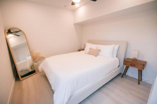 a bedroom with a white bed and a mirror at Marsh View - Modern Getaway - Mins from Downtown in Saint Augustine