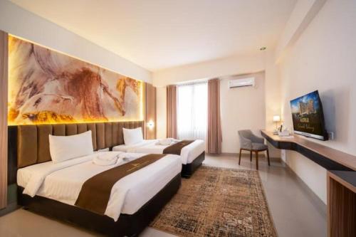 Grand Altuz Hotel Yogyakarta في Seturan: غرفة فندقية بسريرين ولوحة على الحائط