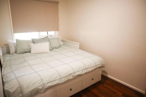 a bedroom with a bed with white sheets and pillows at Home in Lamington in Kalgoorlie