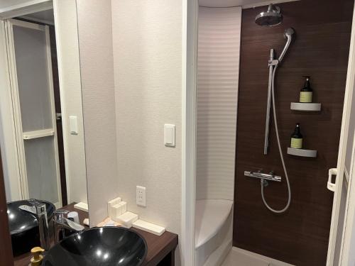 La salle de bains est pourvue d'un lavabo noir et d'une douche. dans l'établissement Miru Nozomi Views, à Niseko