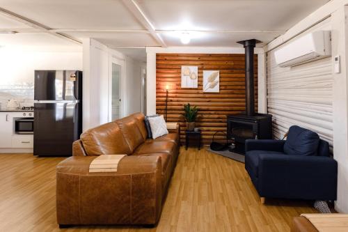 a living room with a leather couch and a stove at Palmers Lane Estate Hunter Valley in Pokolbin