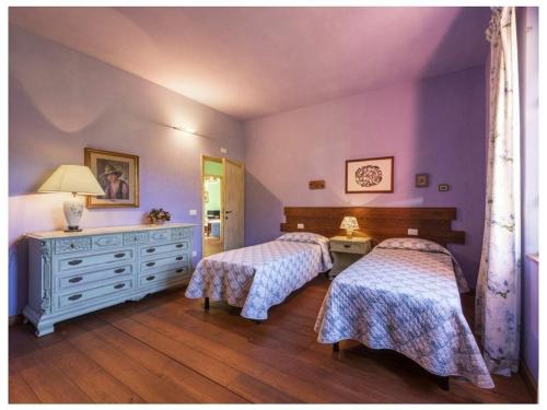 2 camas en un dormitorio con paredes moradas y suelo de madera en Villa Popiglio, en San Marcello Pistoiese