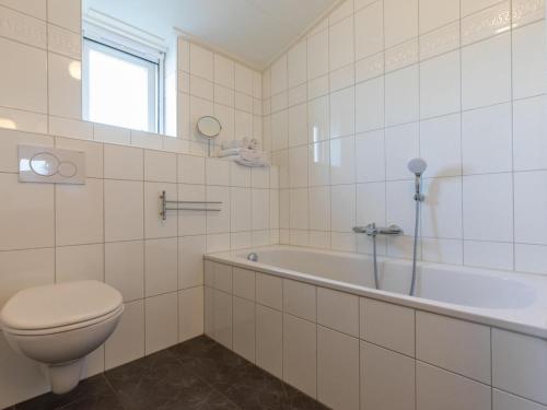 ein weißes Bad mit einem WC und einer Badewanne in der Unterkunft Appealing studio with garden in Koudekerke