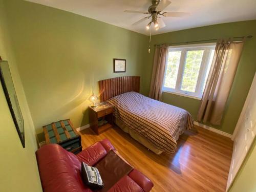 a bedroom with a bed and a couch and a window at Tip-of-Peninsula Lookout Cottage in Tobermory