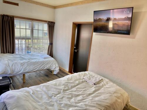 飯山市にあるゲストハウスみどりのベッド2台、壁掛けテレビが備わる客室です。