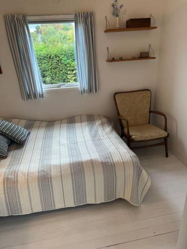 a bedroom with a bed and a chair and a window at 120 m fra stranden med ro og hygge in Kalundborg