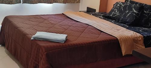 a bed with a brown comforter and a towel on it at Fully Furnished Condo Park Lane Resorts 2314 in Jomtien Beach