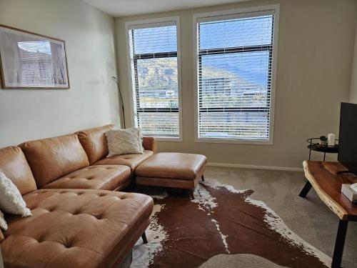 a living room with a brown couch and two windows at 16 Tewa St in Queenstown