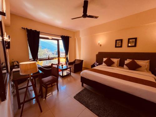 Schlafzimmer mit einem Bett, einem Schreibtisch und einem Fenster in der Unterkunft Ramayan Resort, in City Centre Manali By Ramanand Sagar in Manali