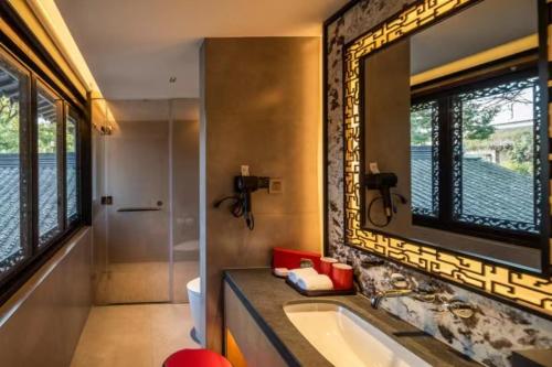 uma casa de banho com uma banheira, um lavatório e um espelho. em Yihe Riverside Suzhou em Suzhou