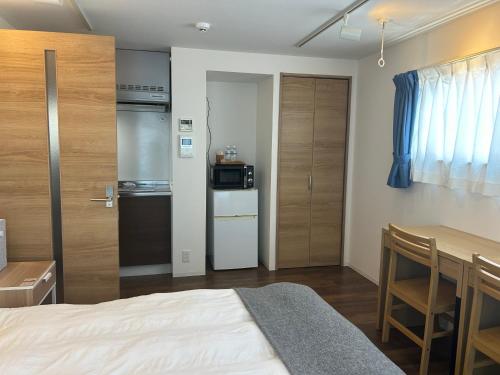 a bedroom with a bed and a table and a kitchen at 湘南海岸 可见海景 江之岛旅游推荐住宿 独立房源 带卫生间、厨房 近海滩 海景房 in Fujisawa