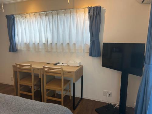a room with a table with two chairs and a television at 湘南海岸 可见海景 江之岛旅游推荐住宿 独立房源 带卫生间、厨房 近海滩 海景房 in Fujisawa
