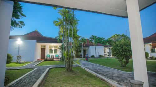 a palm tree in front of a house at Royal Brongto Hotel in Timuran