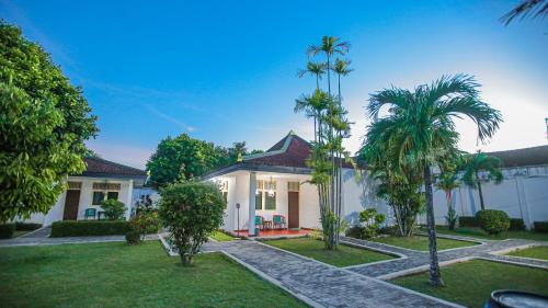 a house with palm trees in front of it at Royal Brongto Hotel in Timuran