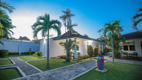 a house with palm trees in front of it at Royal Brongto Hotel in Timuran