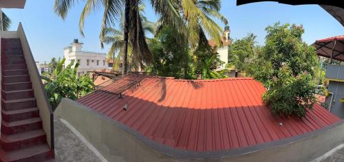 an orange roof on a house with palm trees at KENSON HOMESTAY in Mangalore