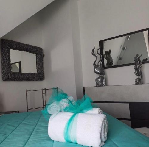 a bed with a pile of towels and a mirror at Casa vacanze Europa in Leonforte