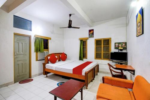1 dormitorio con 1 cama, 1 silla y TV en Goroomgo Upasana Bhubaneswar, en Bhubaneshwar