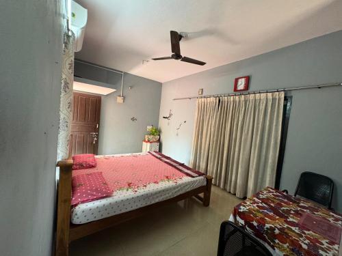 KENSON HOMESTAY في منغالور: غرفة نوم بسرير ومروحة سقف