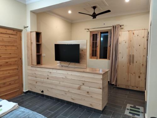 Una habitación con un televisor de pantalla plana en una pared de madera. en Anitra, en Dharamshala