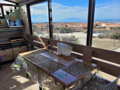 une table en face d'une grande fenêtre avec vue dans l'établissement T3 vue époustouflante proche plage parking Wi-Fi gratuit, au Barcarès