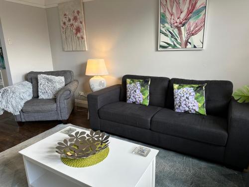 a living room with a black couch and a table at Daisy Cottage on Duke 3BR in Yarram