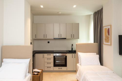 - deux lits dans une cuisine avec des placards blancs dans l'établissement Tokyo Studios, à Chios