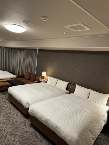 a hotel room with two beds and a couch at Hotel Silk Tree Nagoya in Nagoya