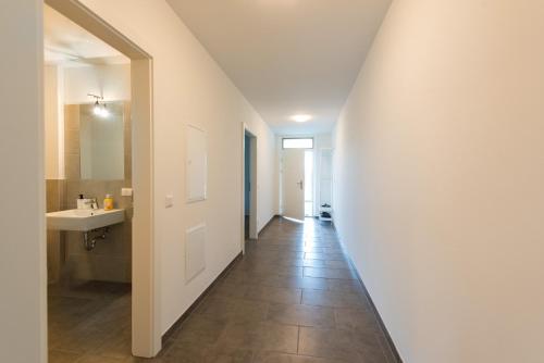 um corredor de uma casa de banho com um lavatório e um espelho em Muzeta Graz - Eco-Friendly Parkview Holiday Apartments in Graz’s Smart City em Graz