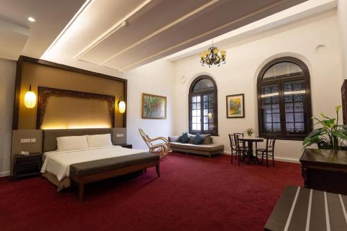 Hotel Puri Melaka في ميلاكا: غرفة نوم بسرير واريكة وطاولة
