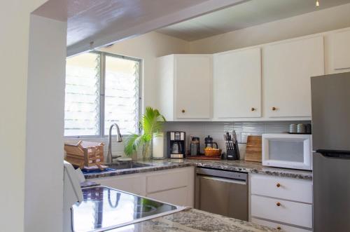 a kitchen with white cabinets and a sink at The Lehua at Keauhou Bay in Kailua-Kona