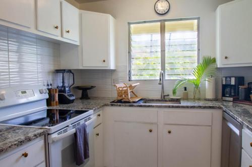 a kitchen with white cabinets and a sink and a window at The Lehua at Keauhou Bay in Kailua-Kona