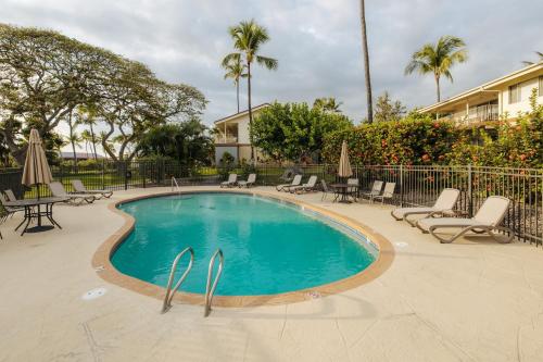 a swimming pool with chairs and umbrellas in a resort at The Lehua at Keauhou Bay in Kailua-Kona