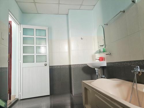 een badkamer met een bad, een wastafel en een spiegel bij Nhà nghỉ thảo ngân in Bình Mỹ