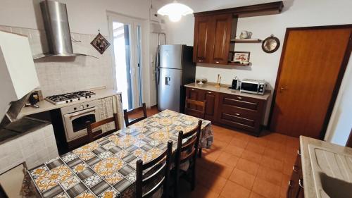 cocina con mesa, fogones y nevera en Villa Egle Belpasso, villa vacanza con piscina, en Belpasso