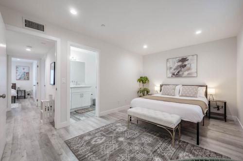 a white bedroom with a large bed and a rug at Modern NOHO Gem! in Los Angeles