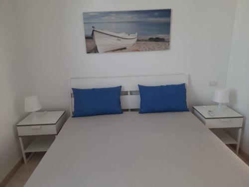 una camera da letto con cuscini blu e un letto con due tavoli di La Vela Apartaments - Porto Cesareo a Porto Cesareo