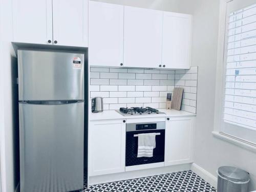 a white kitchen with a refrigerator and a stove at Blue Dreams in Sydney