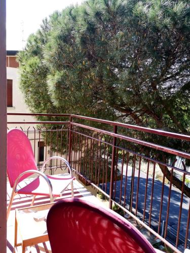 a balcony with two red chairs and a tree at Casa Dorita - Free Coffee Corner 8-12 in Cervia
