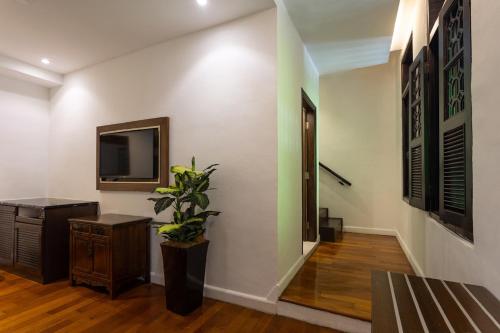 a hallway with a television and a table and a plant at Hotel Puri Melaka in Malacca