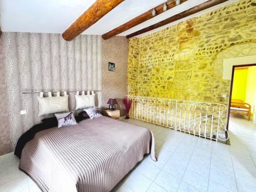 1 dormitorio con cama y pared de piedra en Loca-Moulins, en Saze