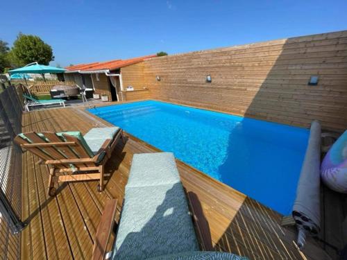 una piscina con sillas y una terraza de madera en La Parenthèse Bucolique, en Aire-sur-la-Lys