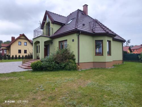 a yellow house with a black roof on a yard at Zielony Dom in Wolin