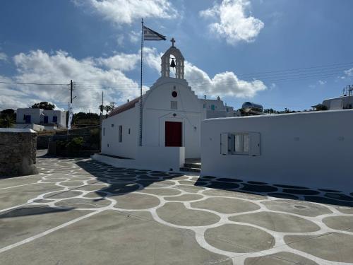 Una iglesia blanca con una bandera encima. en Anais en Mykonos ciudad