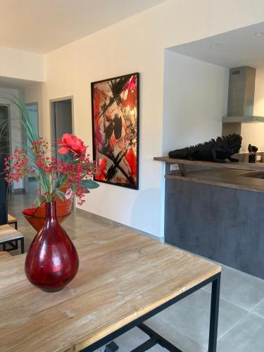un vase rouge avec des fleurs sur une table dans une cuisine dans l'établissement Villa 4 personnes - 2 chambres - Figari, à Figari