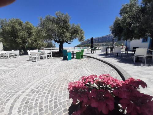 a patio with tables and chairs and pink flowers at Borgo Rurale Cares in Dorgali