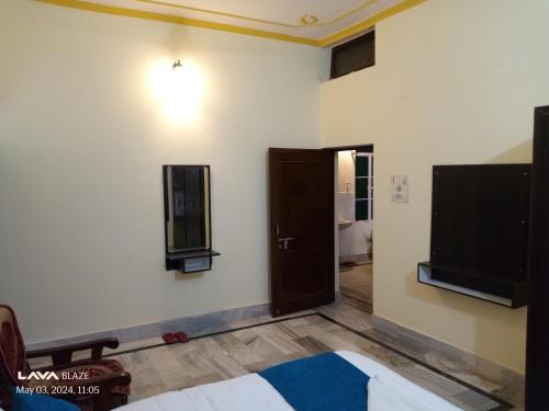 バラナシにあるRani Villa Family HomeStayのベッド1台と壁掛けテレビが備わる客室です。