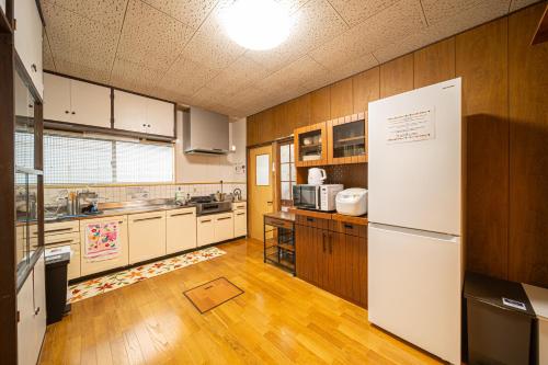 高千穂町にあるTakachiho Himuka no Yadoのウッドフロアの広いキッチン(白い冷蔵庫付)