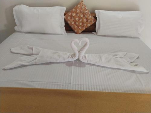 a bed with two white towels on it at Katakeri Deluxe Holiday Homes in Madikeri