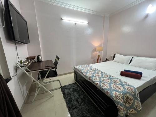 een slaapkamer met een bed, een bureau en een televisie bij Fully Furnished Studio Apartment in Pune